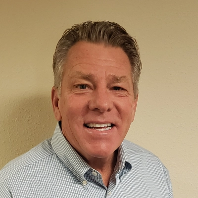 Chiropractor Craig Wink Smiling In Collared Shirt On Beige Background